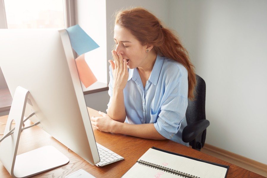 Une femme baille devant son écran de PC