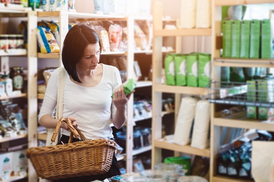 une femme fait les courses et regarde les étiquettes alimentaires